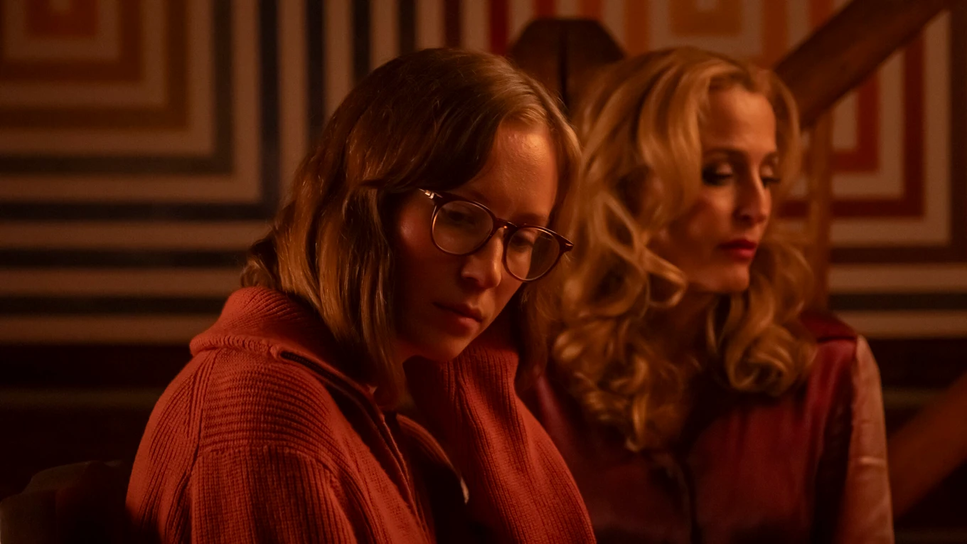 Hannah Einbinder and Gillian Anderson in a red-lit room, looking two different directions.