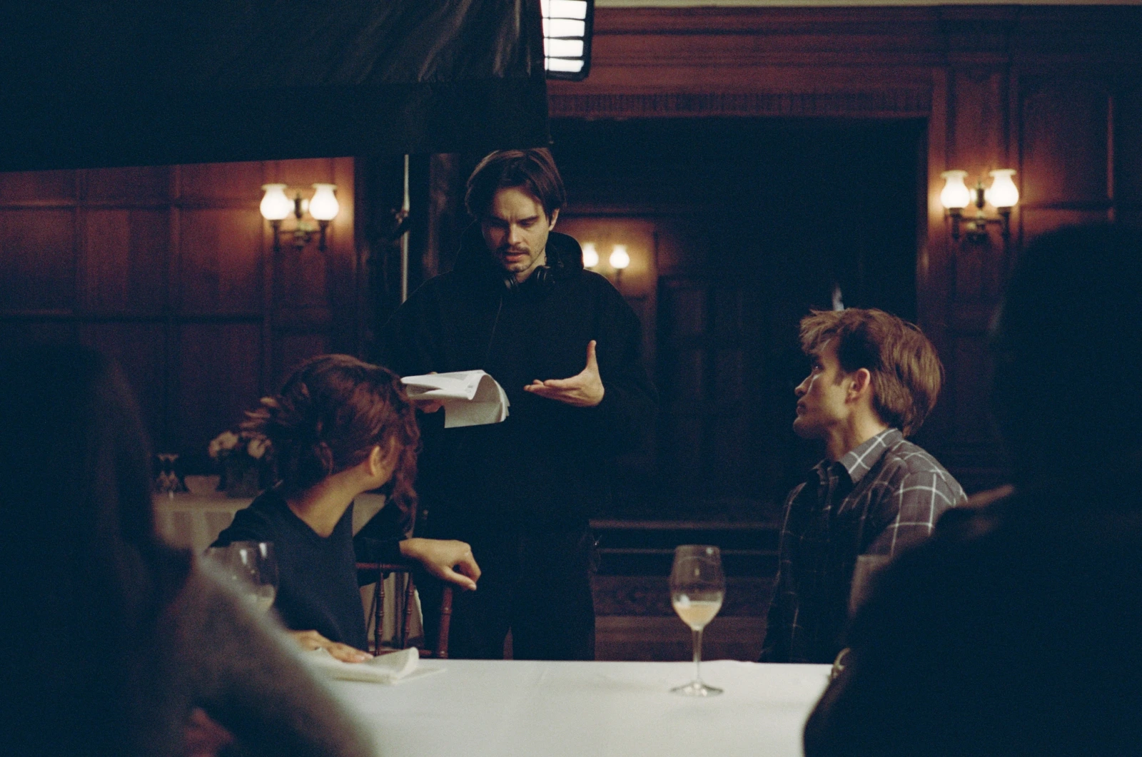 Kristoffer Borgli speaking to Zendaya and Robert Pattinson, who are sitting down at a dinner table.